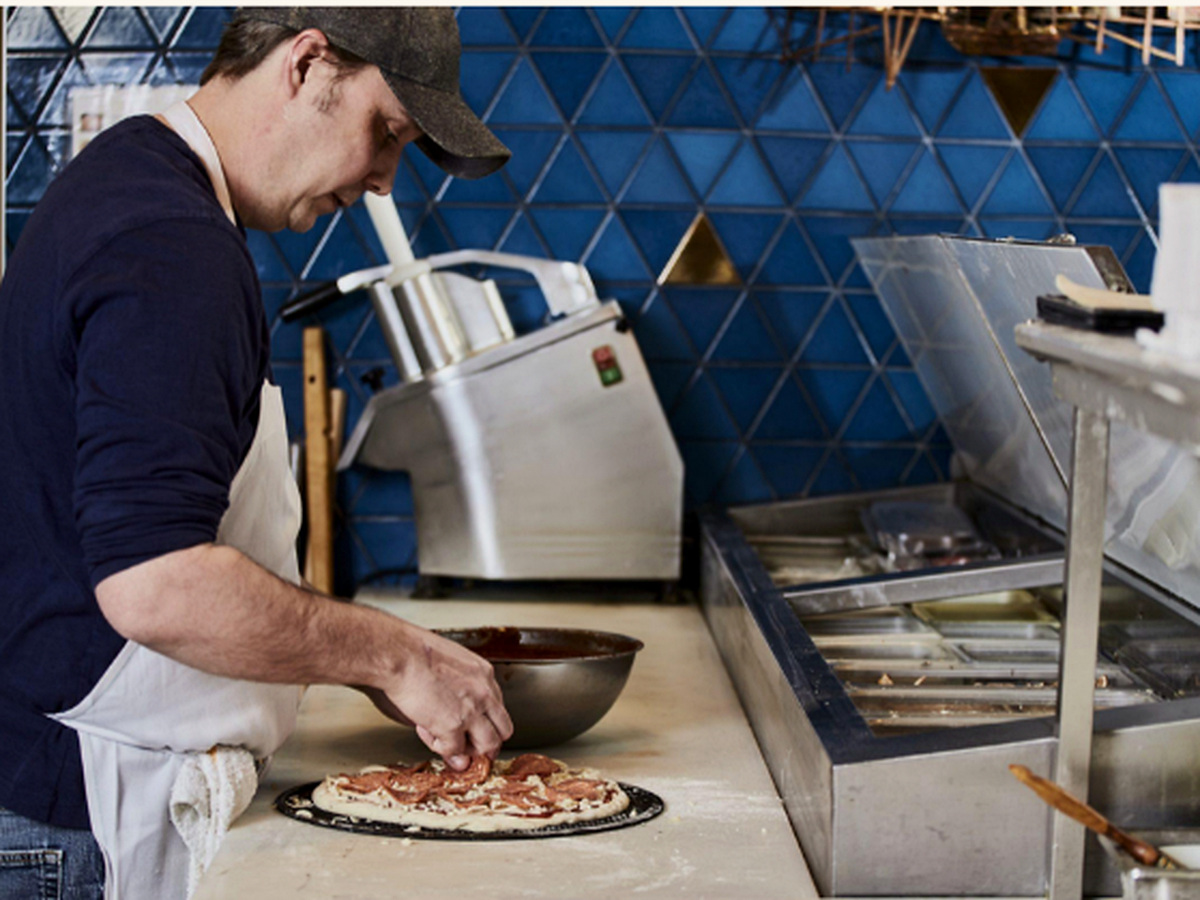 Capri pizza being topped by hand